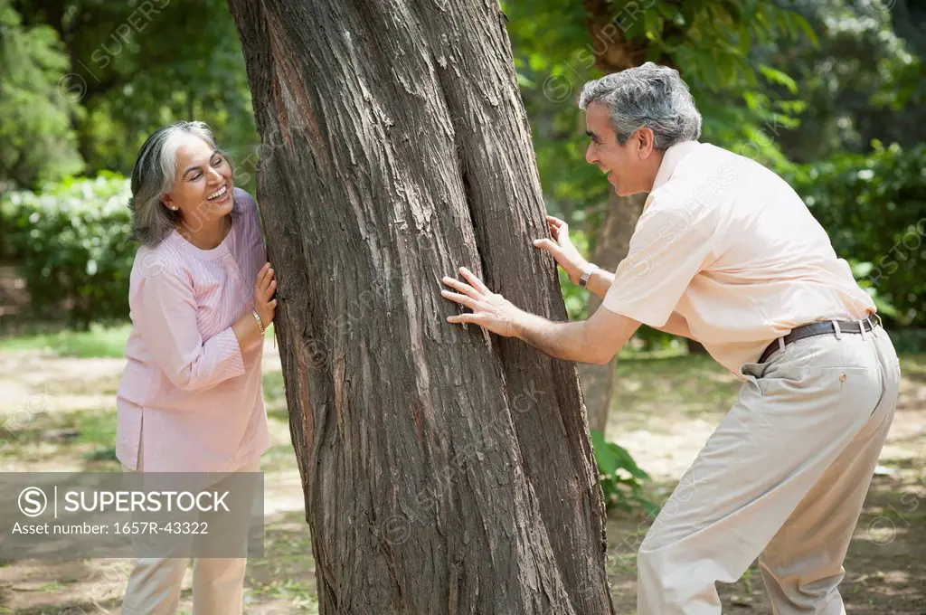 Mature couple playing hide and seek in a park, Lodi Gardens, New Delhi, India