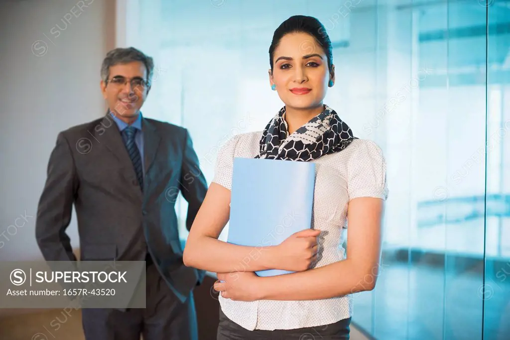 Businesswoman holding a file with a businessman standing behind her