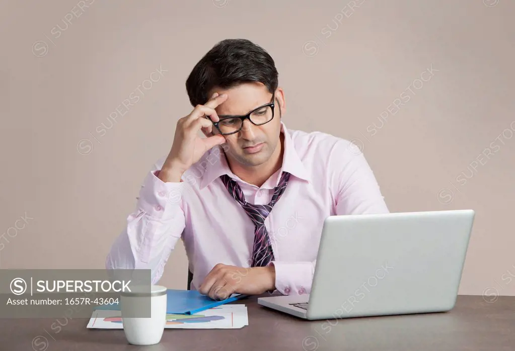 Businessman looking at a laptop and thinking