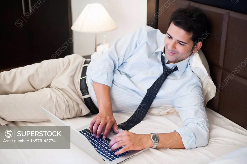 Businessman working on a laptop on the bed