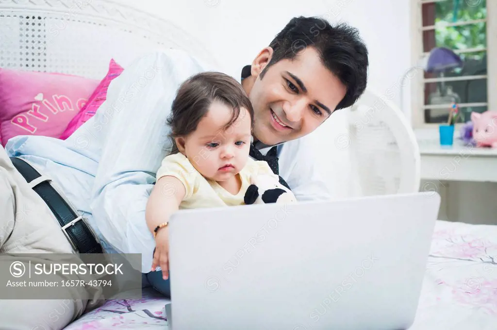 Businessman with his baby working on a laptop