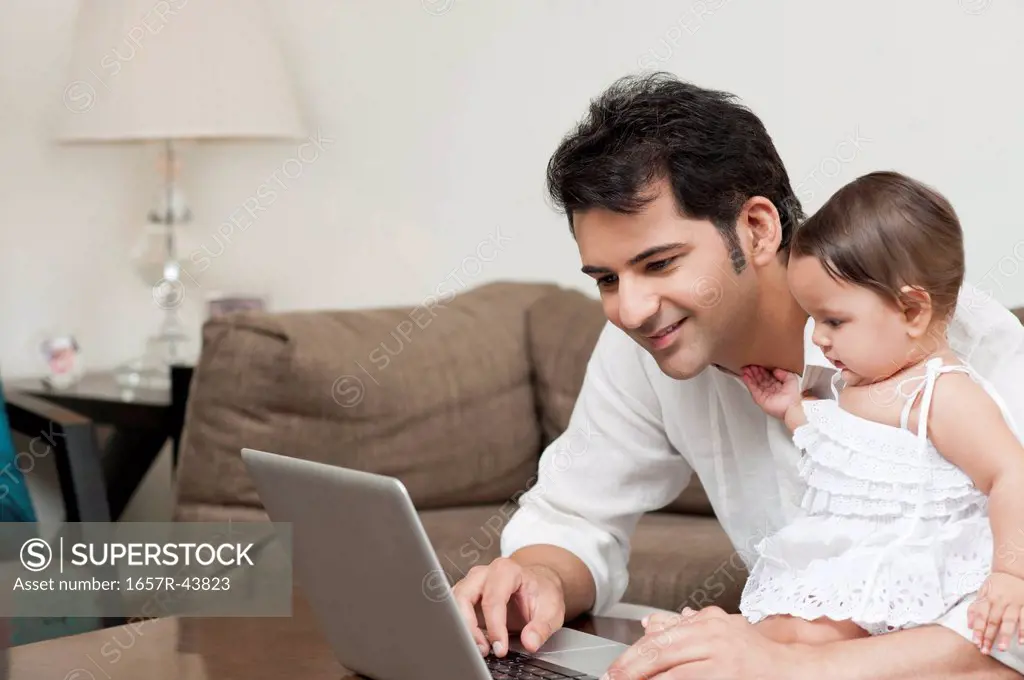 Man using a laptop with his daughter sitting with him