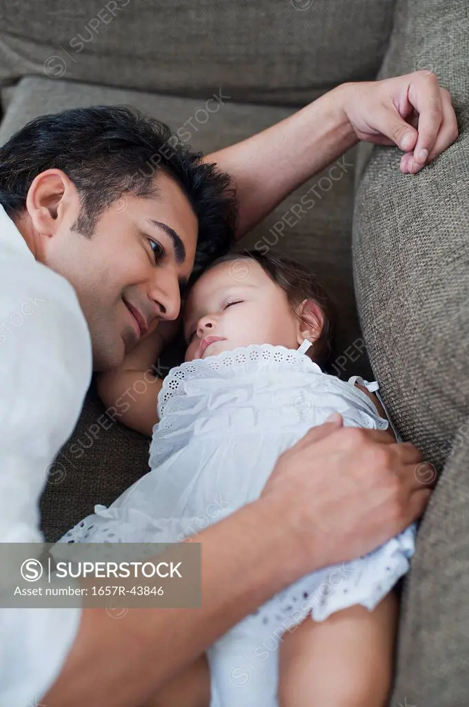 Man lying beside his sleeping daughter