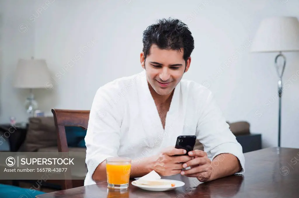 Businessman reading a SMS on a mobile phone at breakfast table