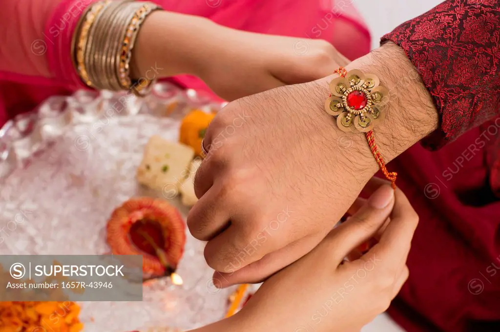 Teenage girl tying rakhi on her brother wrist