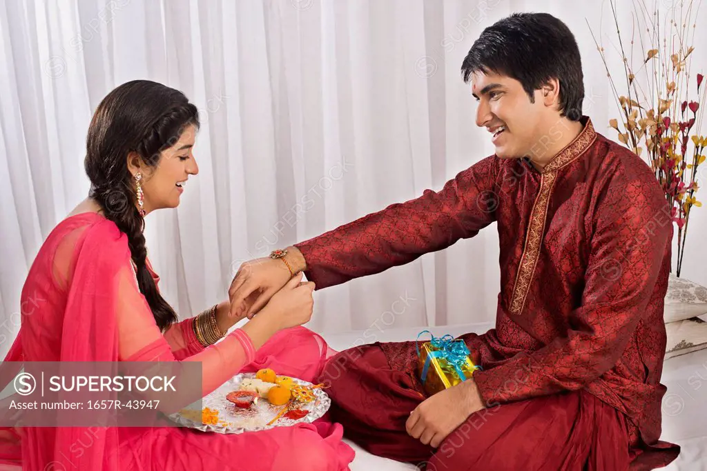 Teenage girl tying rakhi on her brother wrist