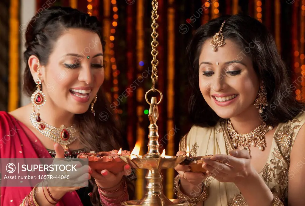 Female friends holding oil lamps on Diwali
