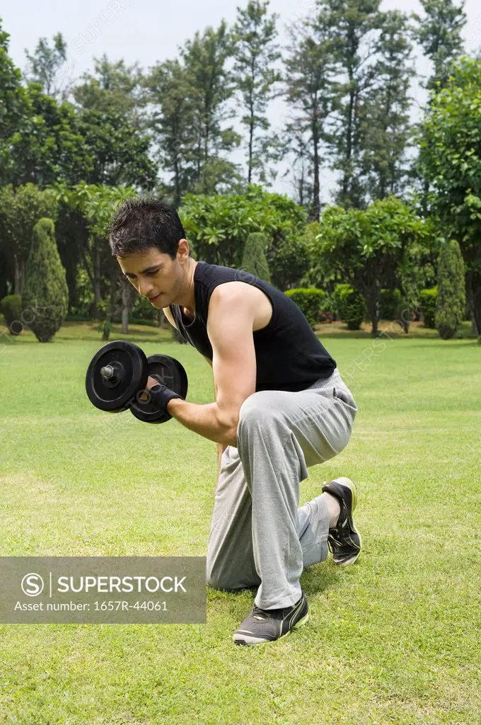 Man exercising with dumbbell in a park