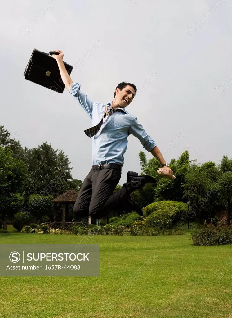 Businessman jumping in a park