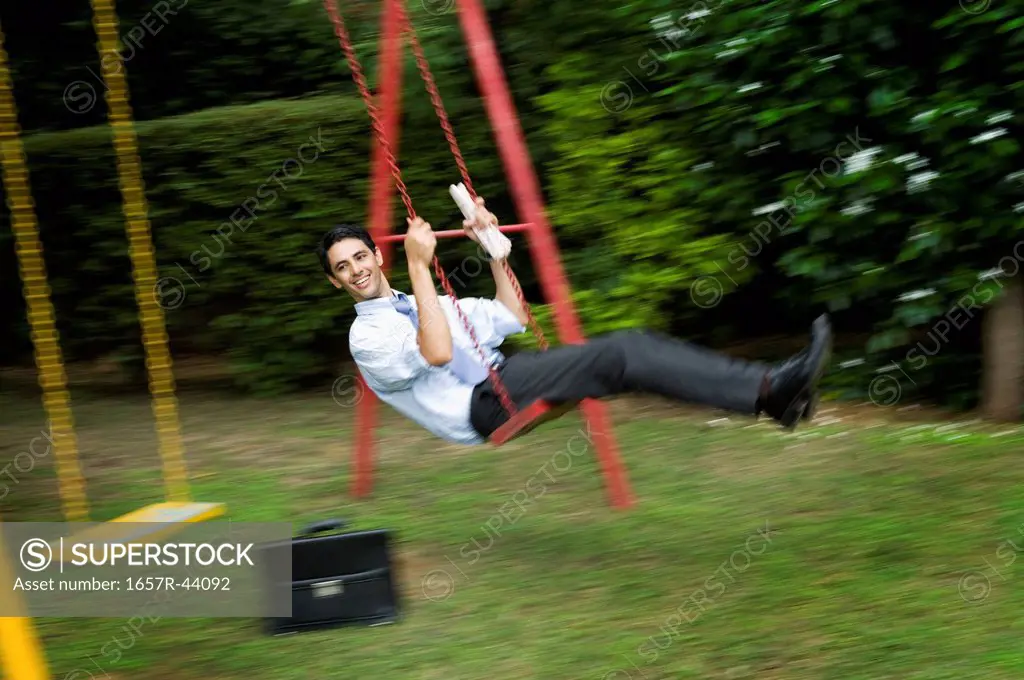 Businessman enjoying a swing in a park