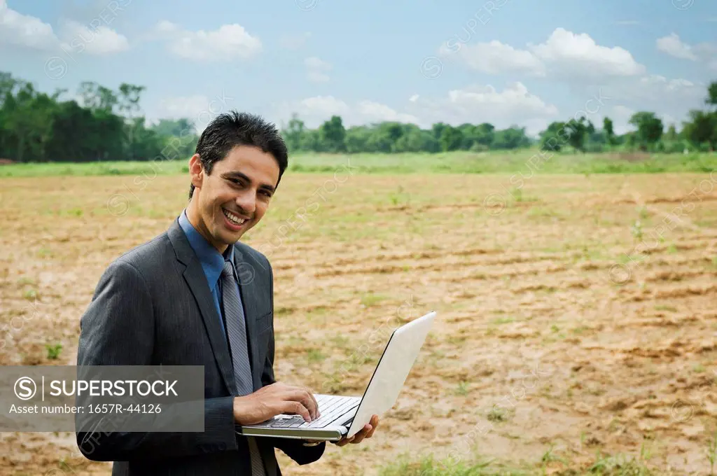 Businessman using a laptop in a field