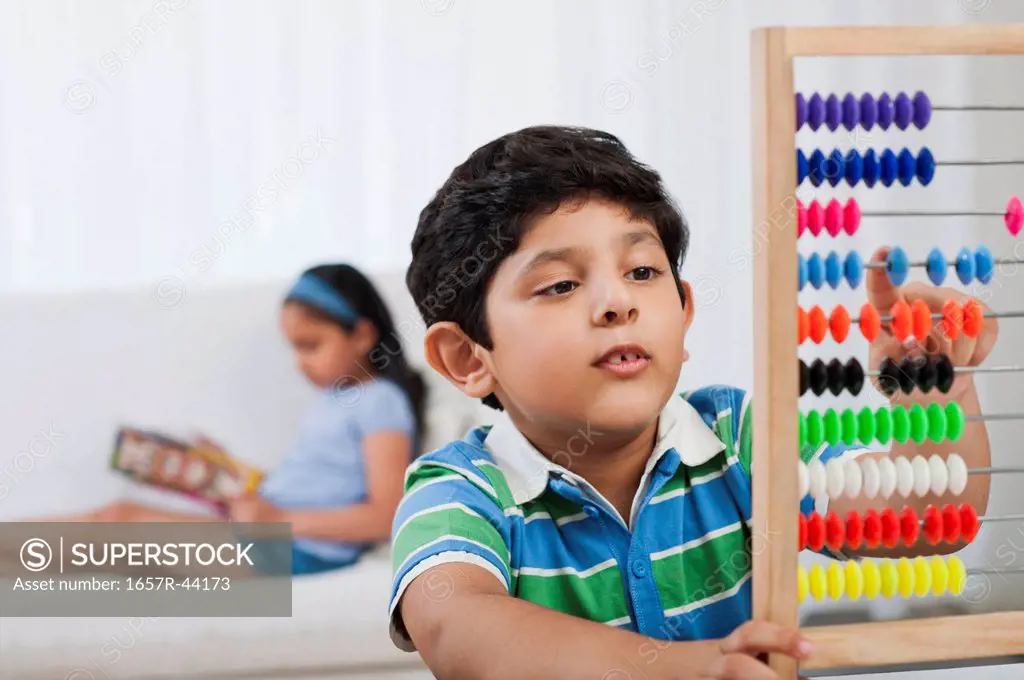 Boy using an abacus with his sister in the background
