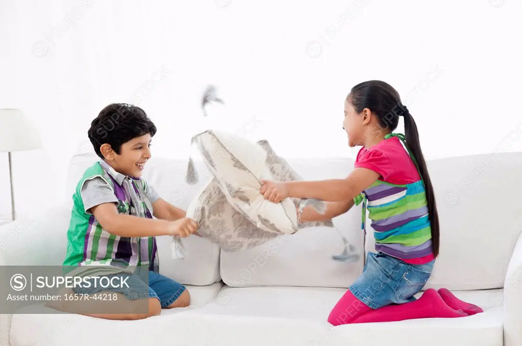 Children pillow fighting on a couch
