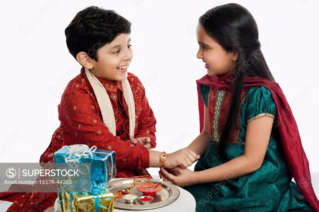 Girl tying rakhi on her brother wrist