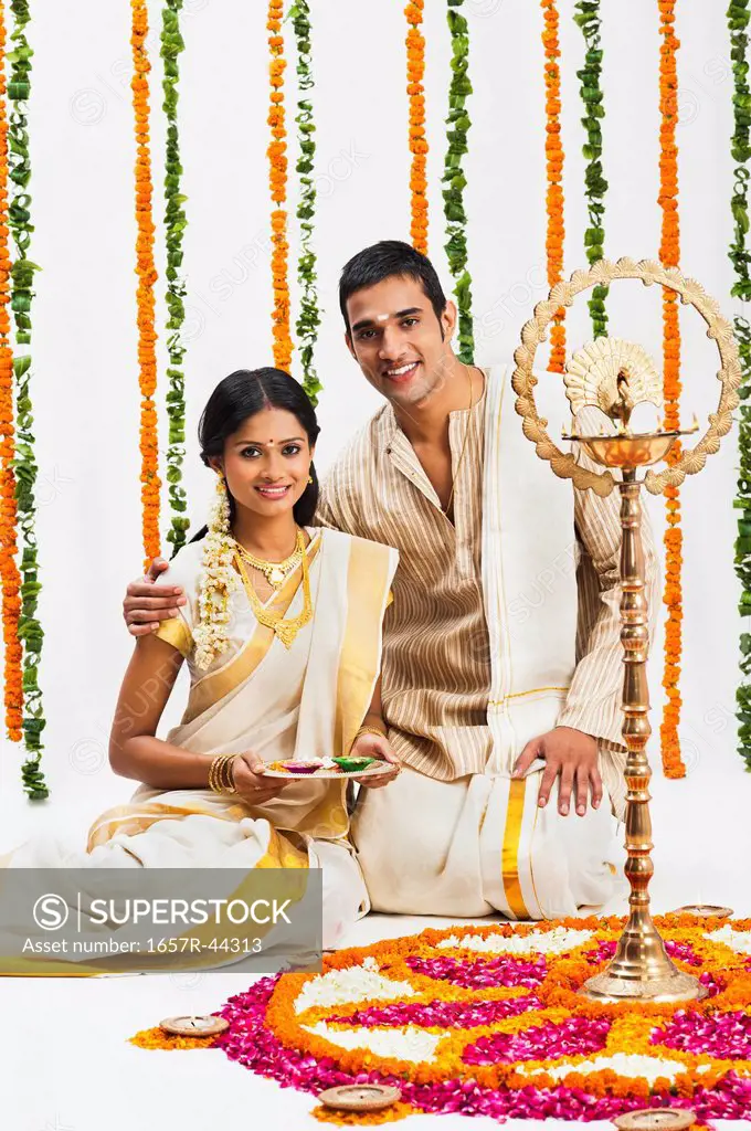 South Indian couple near a rangoli of flowers at Onam
