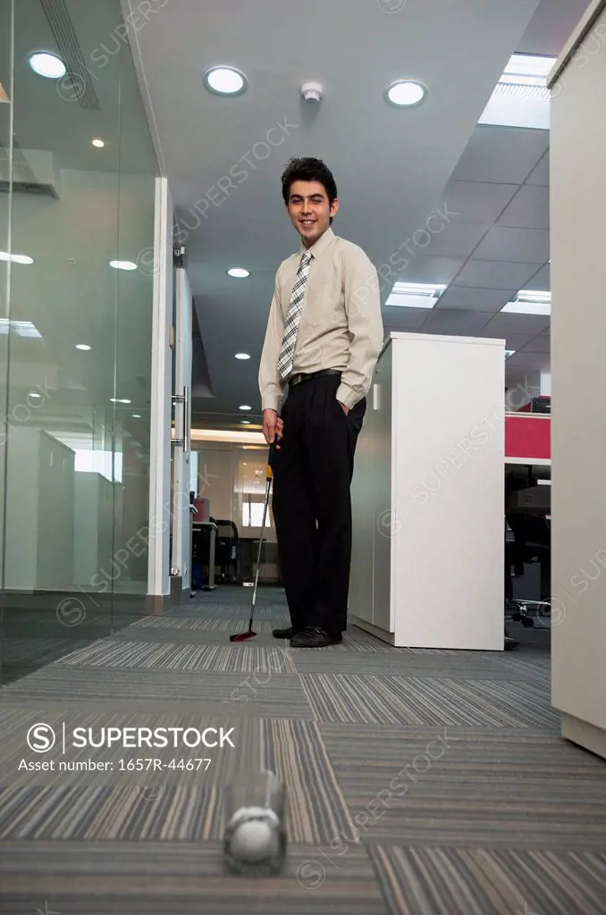 Businessman playing golf in office