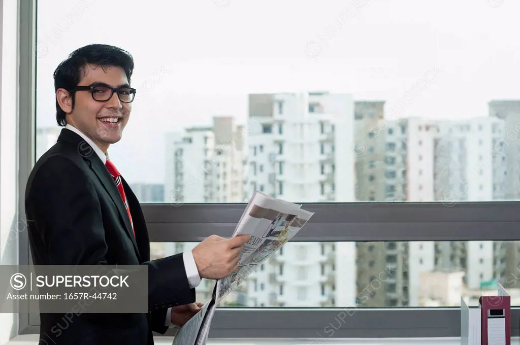 Businessman holding a newspaper and smiling