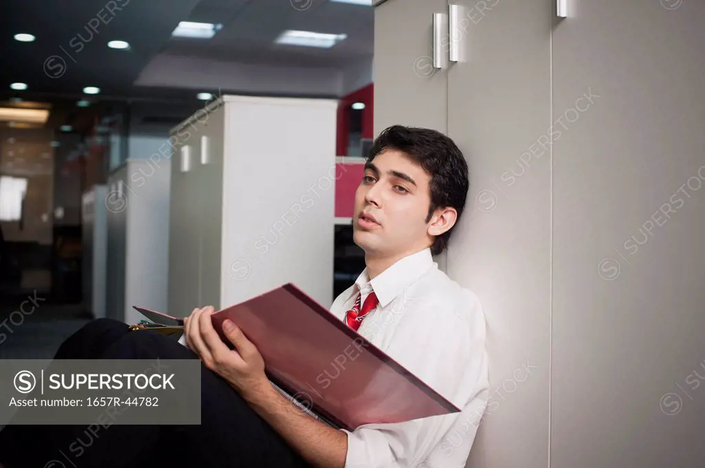 Businessman leaning against a cabinet in the corridor