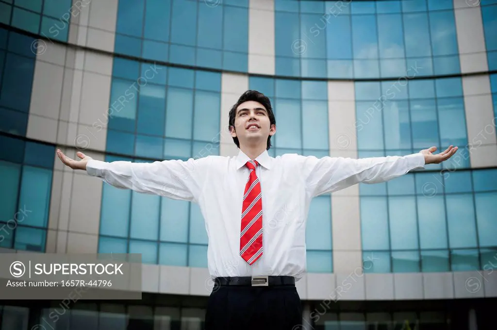 Man standing with his arms outstretched outside an office building