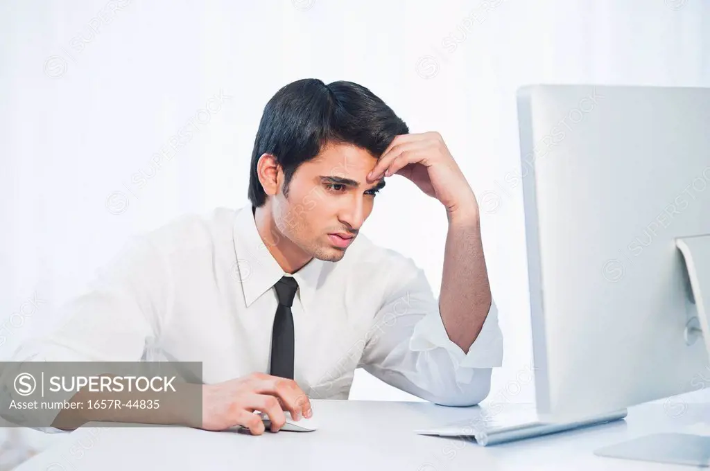 Businessman looking at a desktop pc and thinking