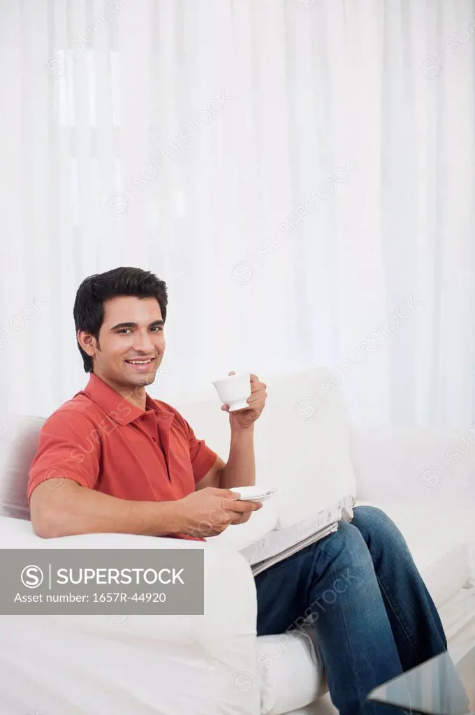 Man sitting on a couch and drinking coffee