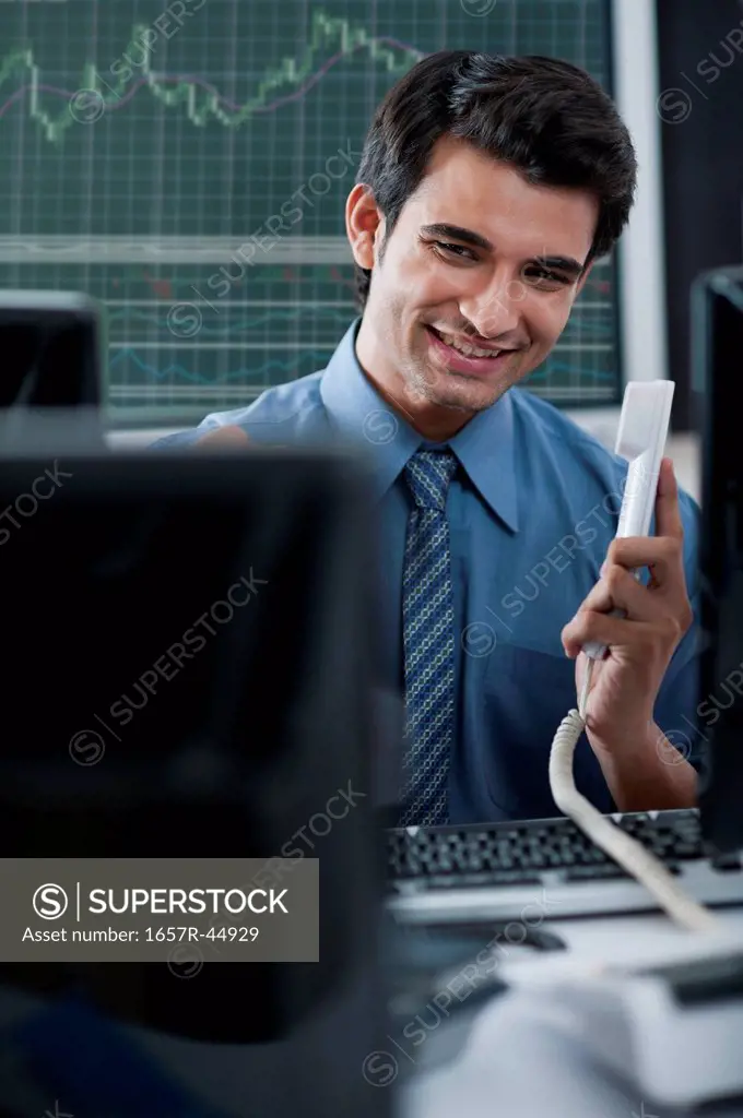 Businessman holding phone receiver and smiling