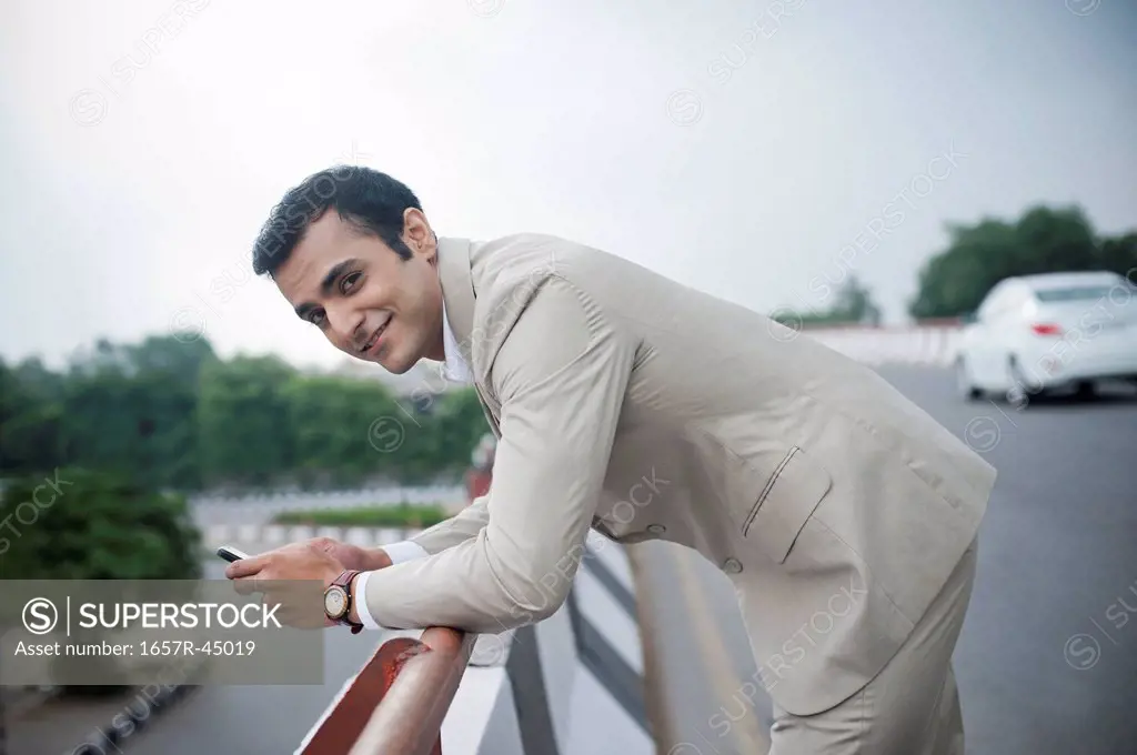 Portrait of a businessman text messaging on a mobile phone at a flyover