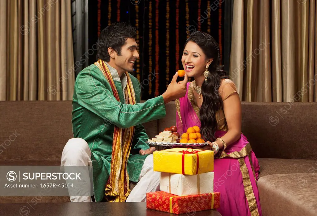 Man feeding laddoo to his girlfriend on Diwali