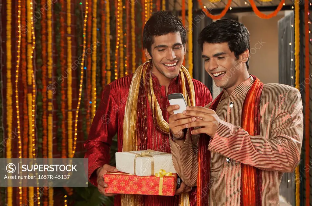 Male friends text messaging on a mobile phone on Diwali