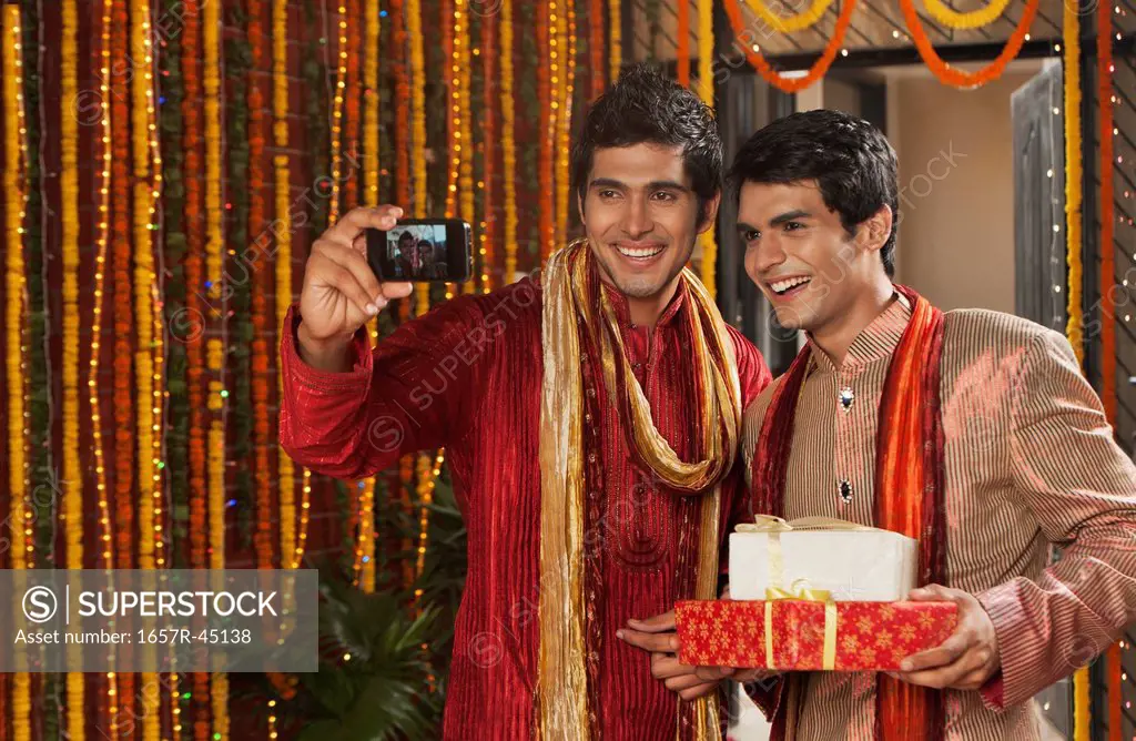 Male friends taking a picture of themselves with a mobile phone on Diwali