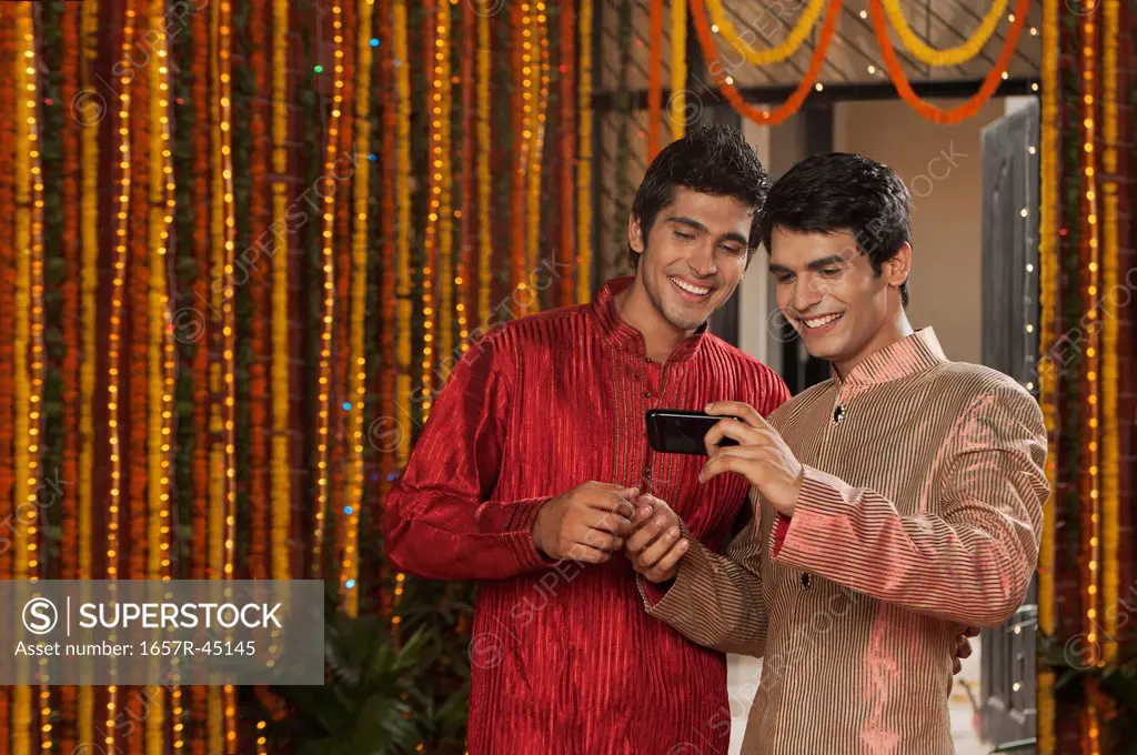 Male friends text messaging on a mobile phone on Diwali