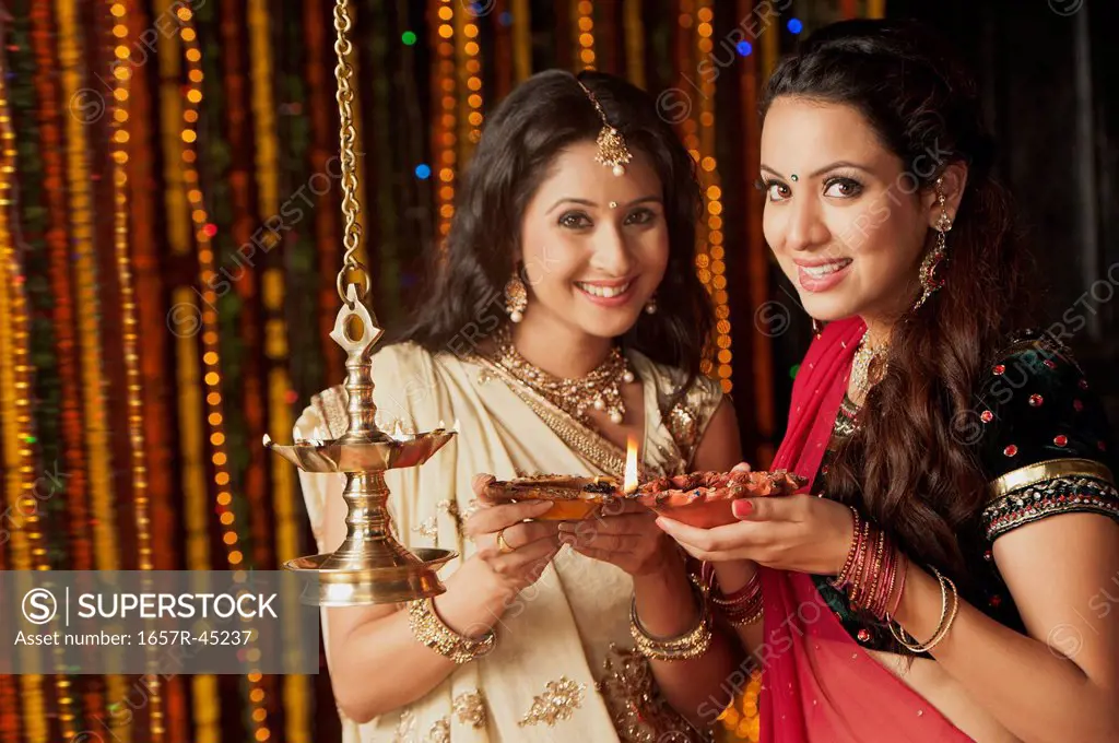 Female friends burning oil lamps on Diwali