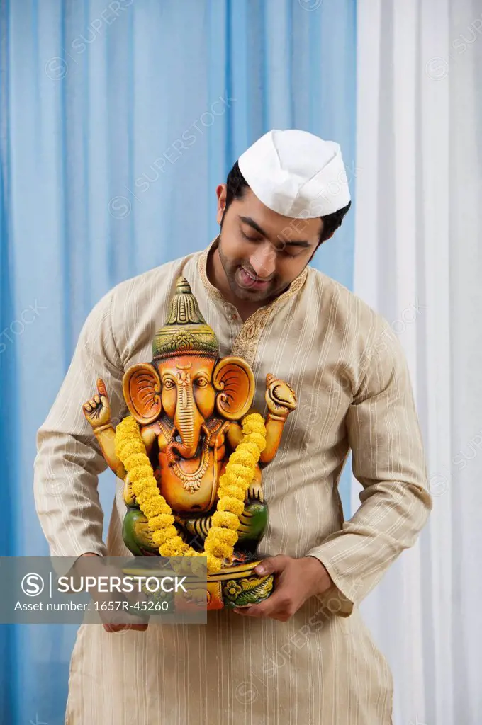 Maharashtrian man holding an Idol of Lord Ganesha during Ganesh Chaturthi festival