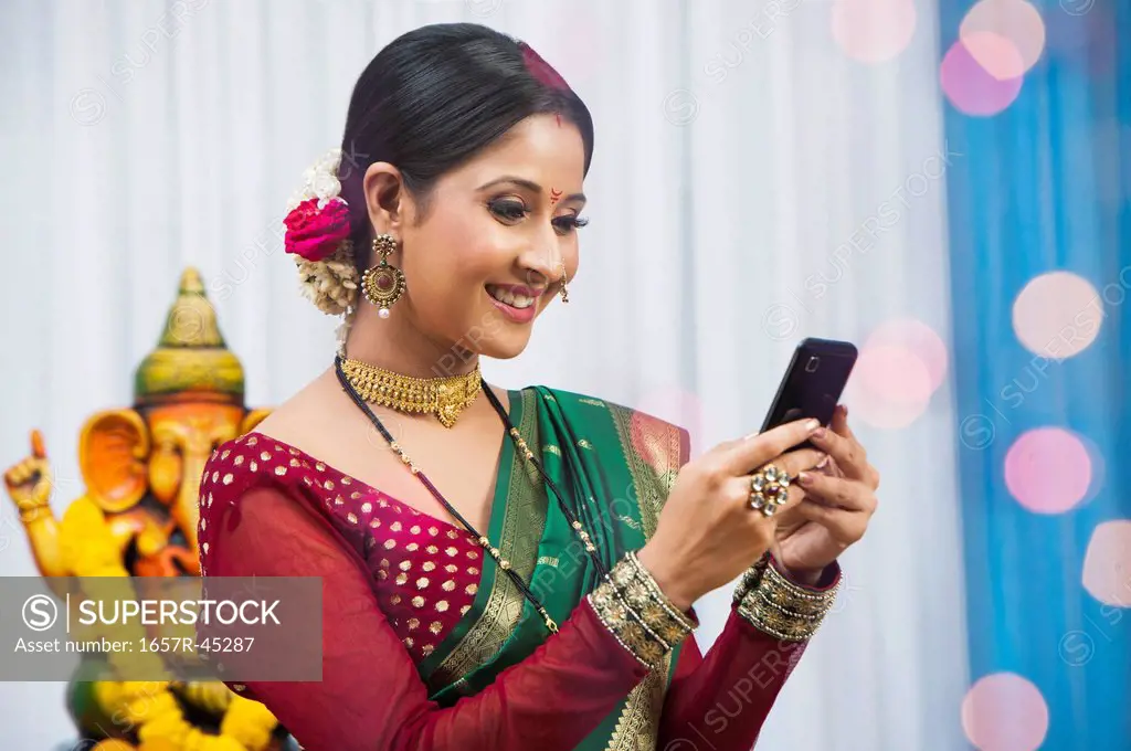 Maharashtrian woman text messaging on a cell phone during Ganesh Chaturthi festival