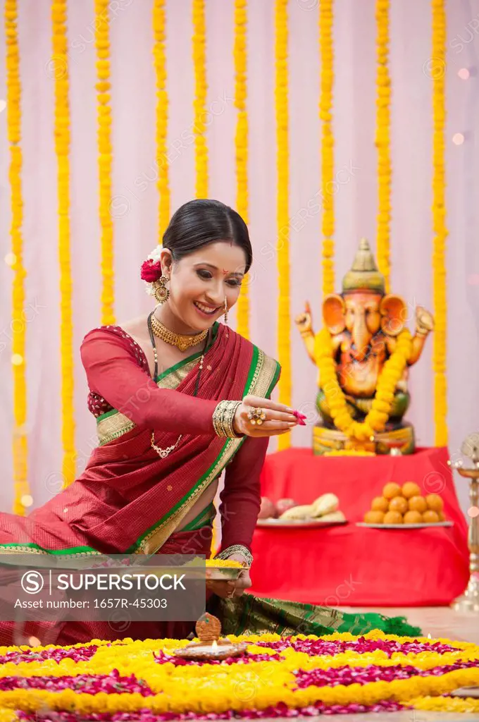 Maharashtrian woman making flower rangoli during Ganesh Chaturthi festival