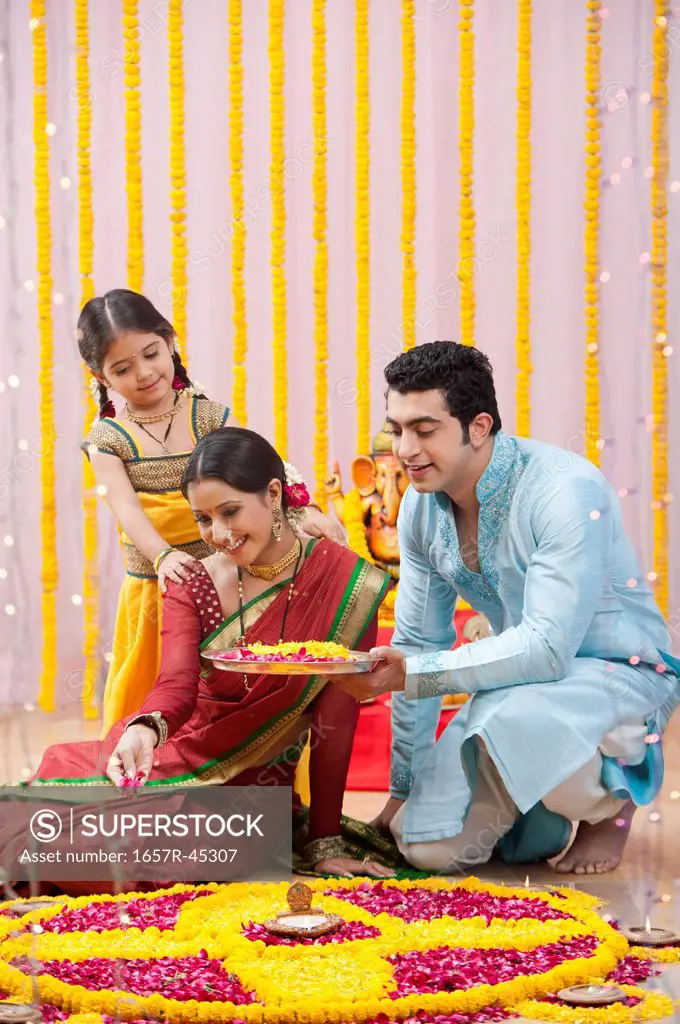 Maharashtrian family making flower rangoli during ganesh chaturthi festival