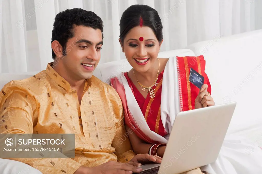 Couple doing online shopping with a credit card and smiling