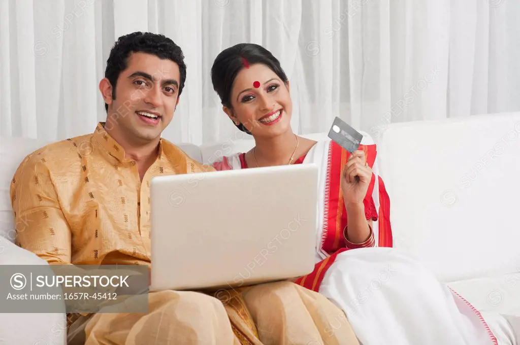 Bengali couple doing online shopping with a credit card and smiling