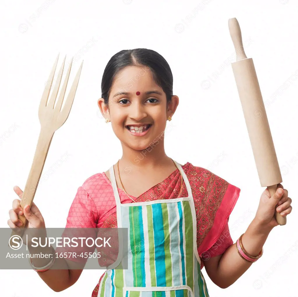 Girl imitating like woman holding rolling pin with a wooden fork