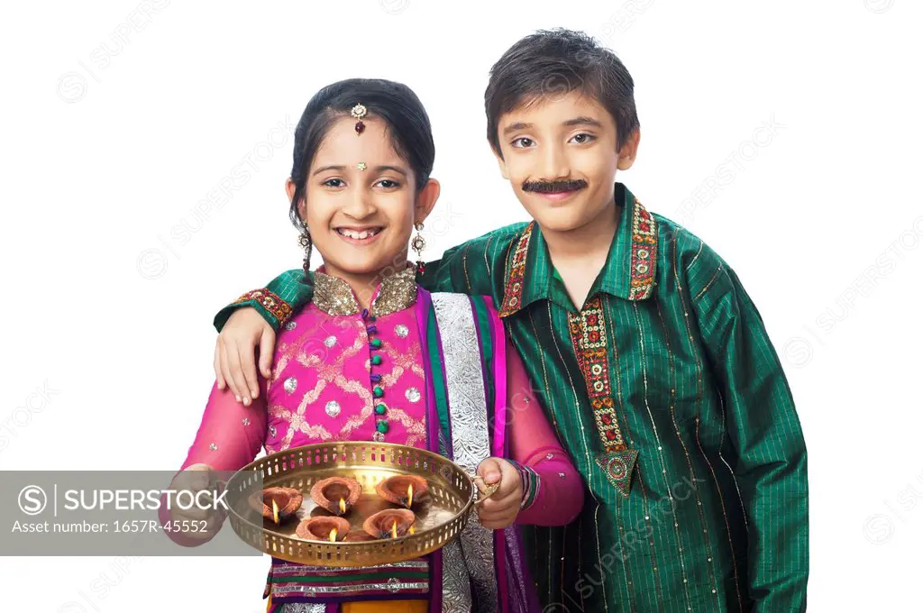 Two children imitating like couple holding oil lamps and smiling on diwali