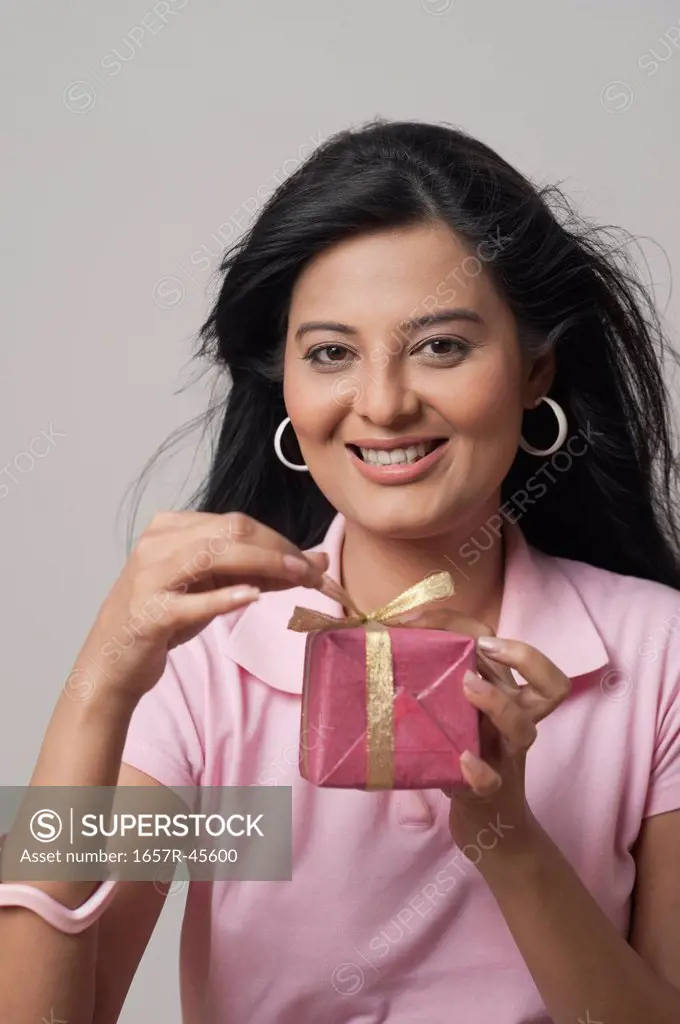 Portrait of a woman opening a gift box and smiling