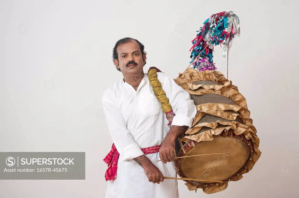 Bengali man playing dhol (A large drum used to play during festival and celebration in India)