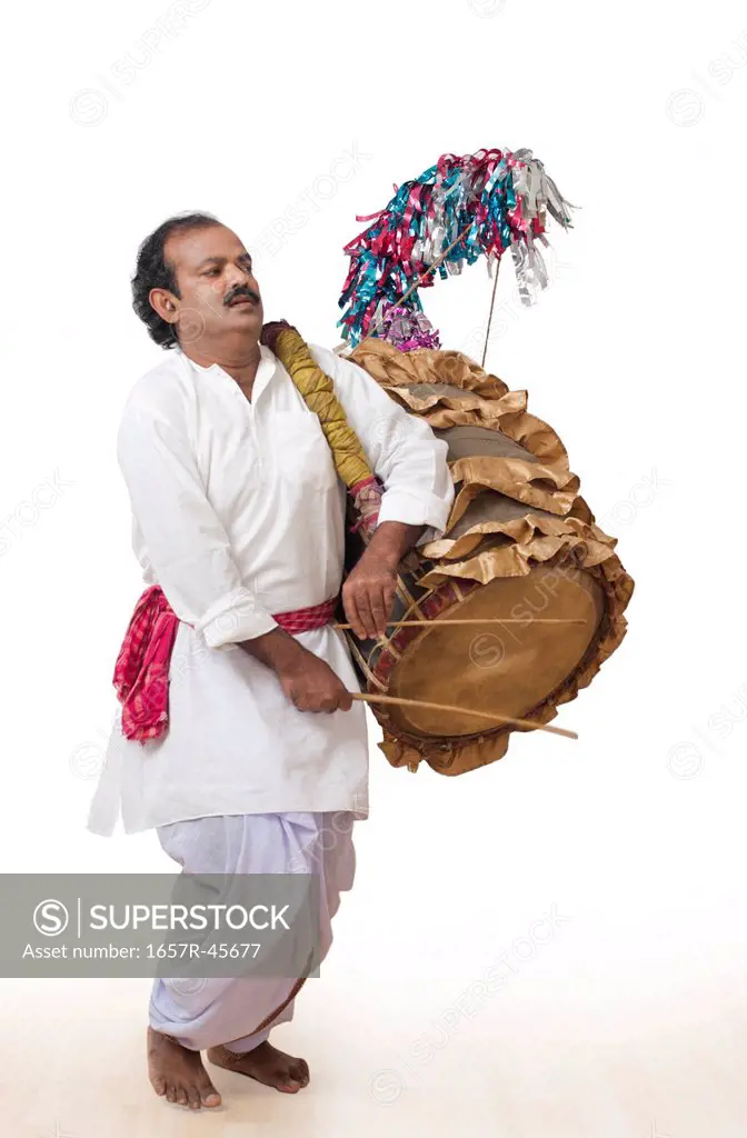 Bengali man playing dhol (A large drum used to play during festival and celebration in India)