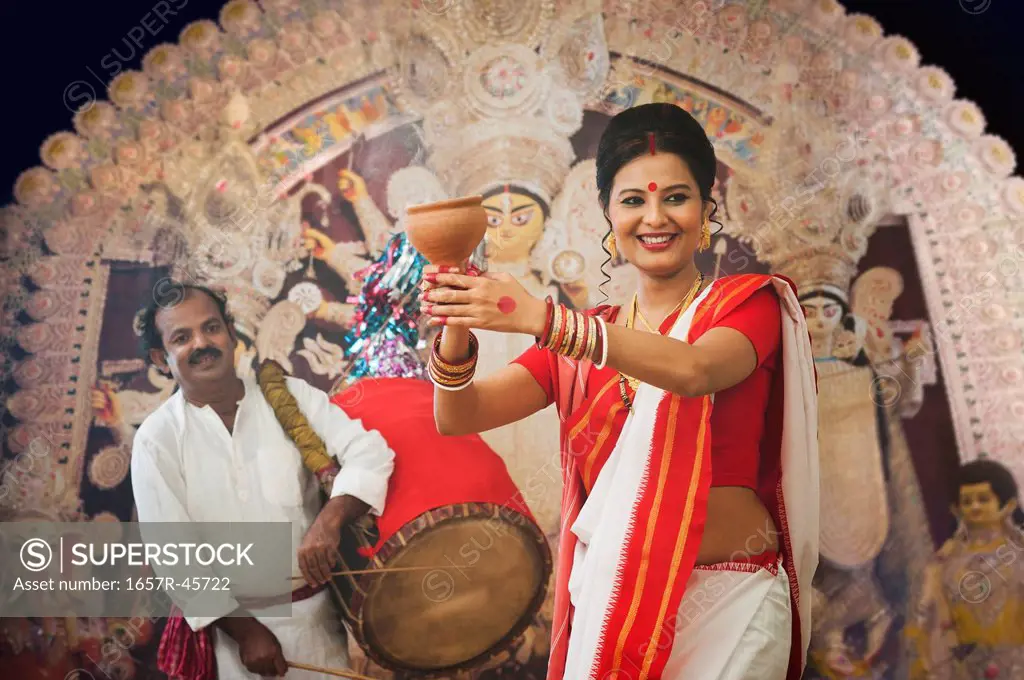 Bengali woman performing Dhunachi Dance and a Dhaki playing Dhak at Durga Puja