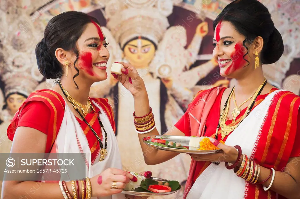 Bengali women feeding Barfi to each other at Durga Puja