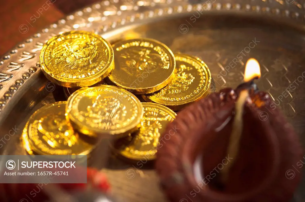 Close-up of Diwali puja thali with golden coins and a diya
