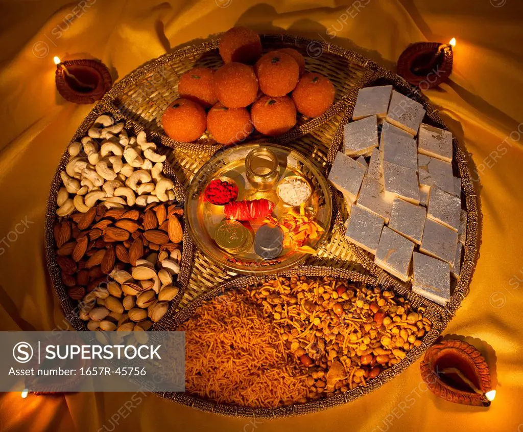 Assorted Diwali sweets and snacks with Diwali diyas