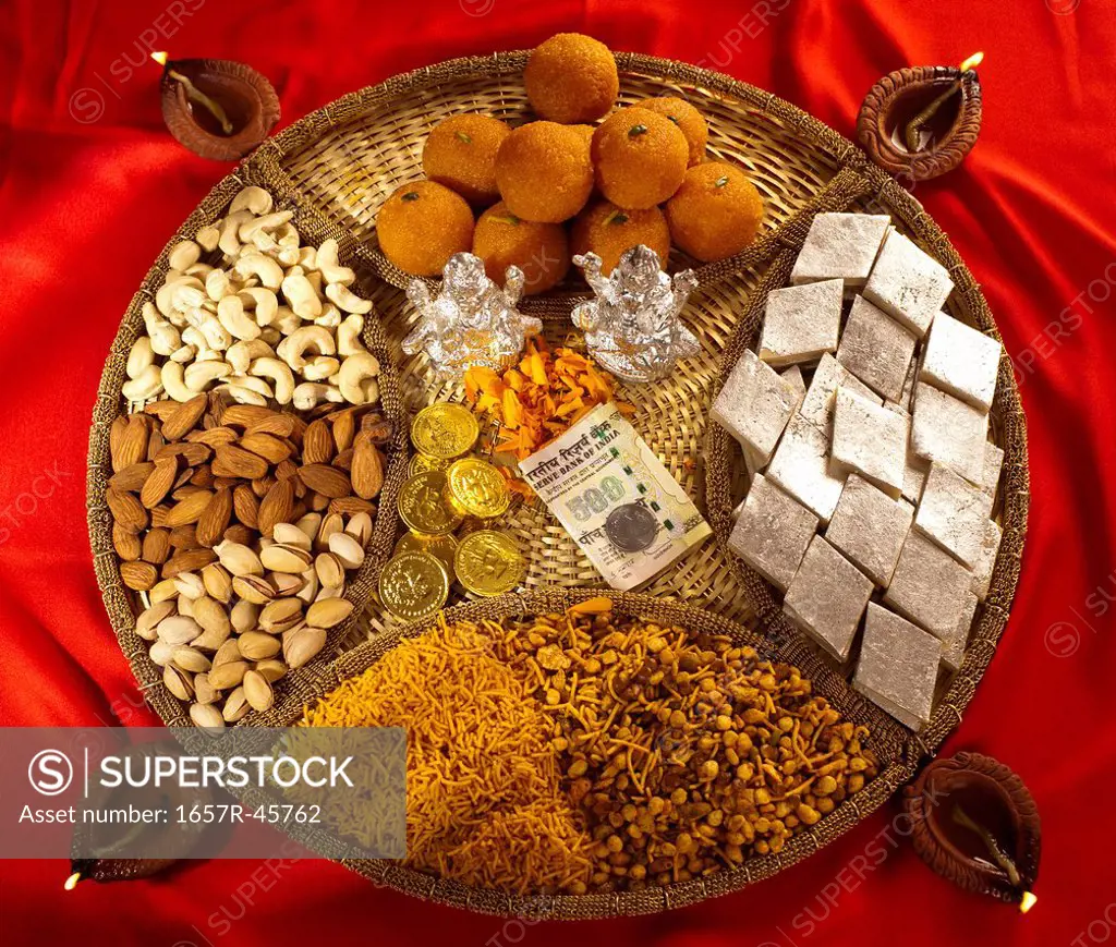 Assorted Diwali sweets and snacks with Diwali diyas