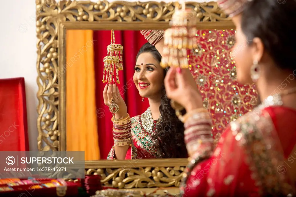 Reflection of a bridal woman in mirror putting on bangles