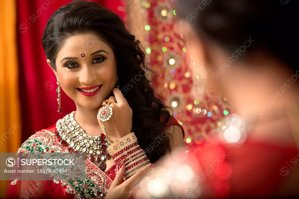 Reflection of a bridal woman in mirror applying lipstick on her lips